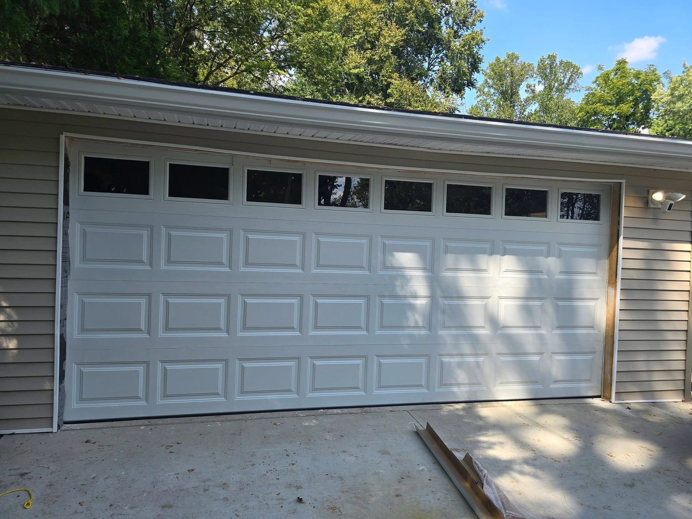 Completed white garage door installed on a residential home exterior