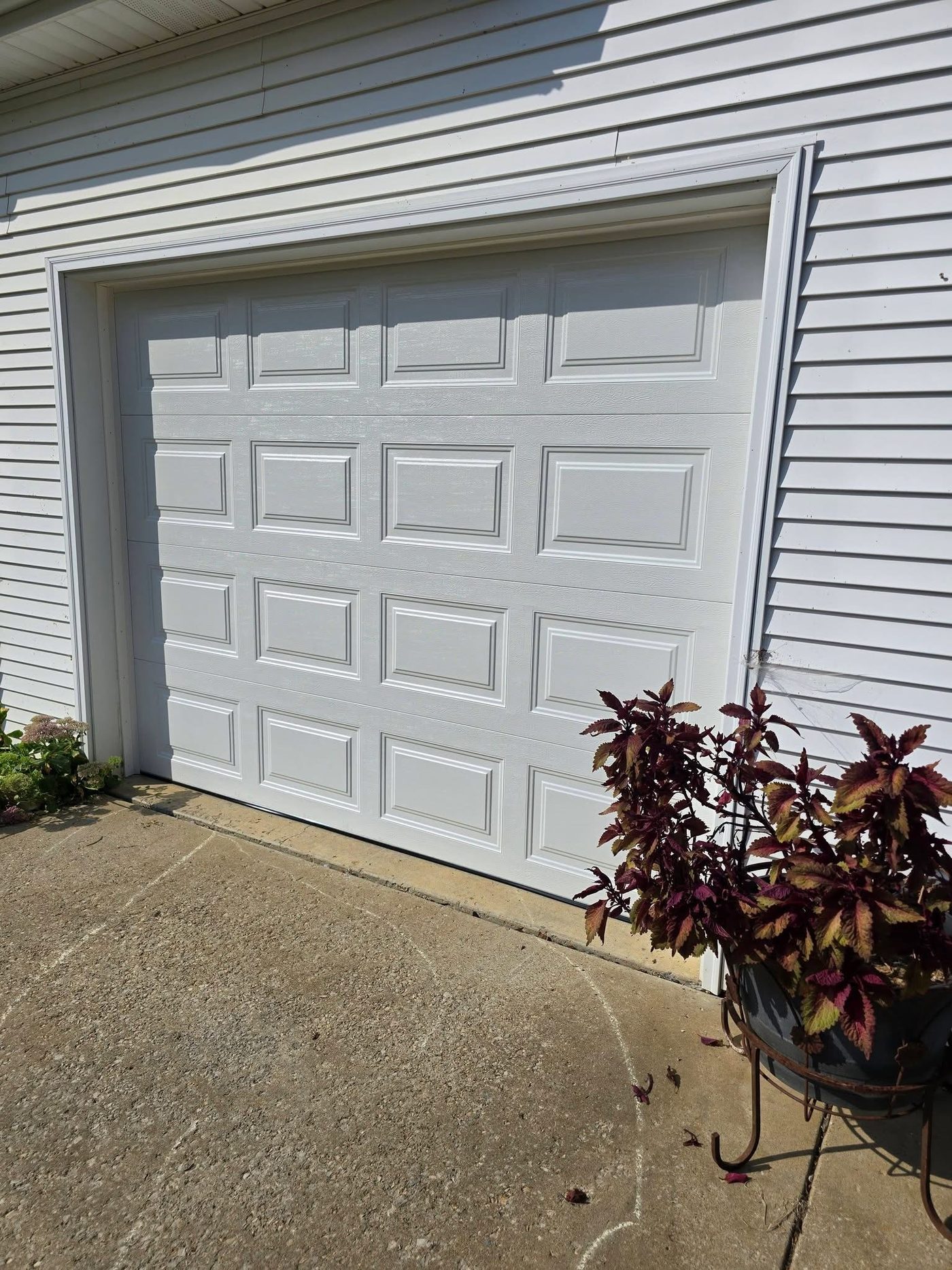 Completed single white garage door installed on a home exterior