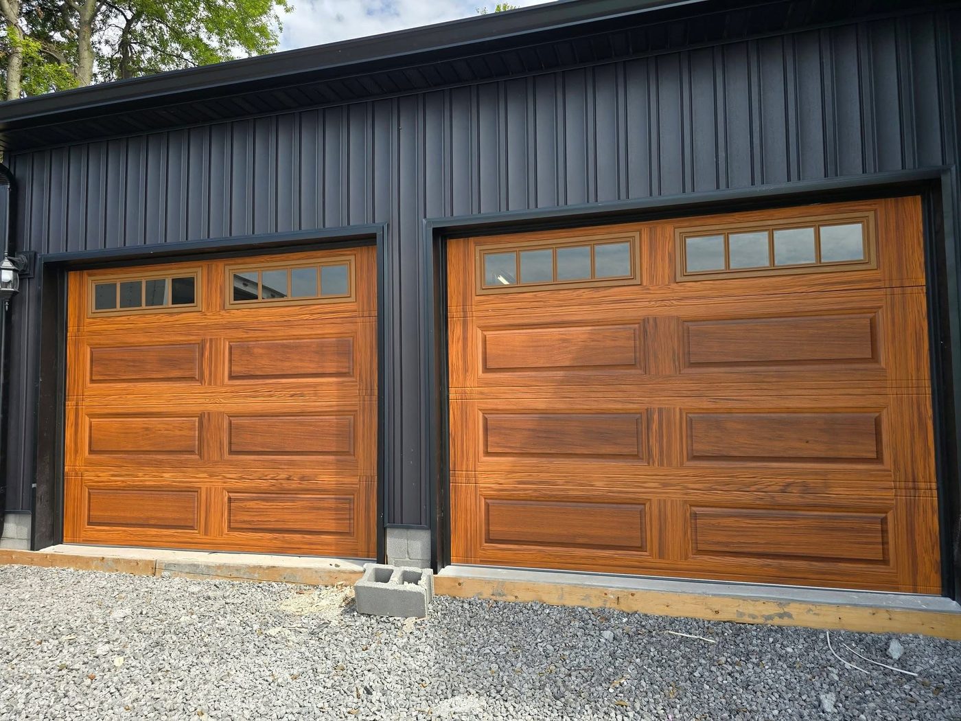 Completed wood-grain garage door installation on a metal building